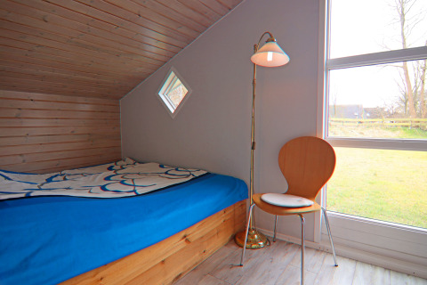 Camera accogliente presso Holiday home «in Hünning», Germania, con letto, sedia e ampia finestra.