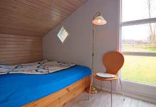 Hyggeligt værelse i Holiday home «in Hünning», Tyskland, med seng, stol og stor rude med udsigt.