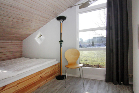 Lyst værelse i Holiday home «in Hünning», Tyskland, med enkeltseng, stol, gulvlampe og stort vindue.