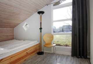 Camera luminosa nella Holiday home «in Hünning», Germania, con letto singolo, sedia e grande finestra.