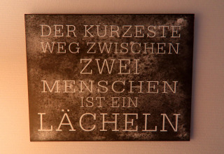 Wandbord in een Duitse lodge met 'Der kürzeste Weg zwischen zwei Menschen ist ein Lächeln.'
