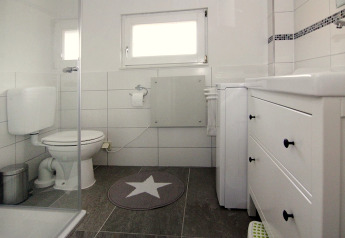 Salle de bain moderne au Holiday home «in Hünning» en Allemagne avec carrelage blanc et sol gris.