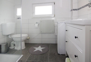Modern bathroom at Holiday home «in Hünning», Germany, featuring white tiles and gray floor tiles.