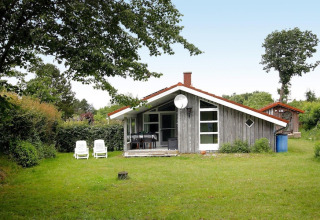 Accogliente casa vacanze a Hünning, Germania, con giardino verde e due lettini bianchi all'esterno.