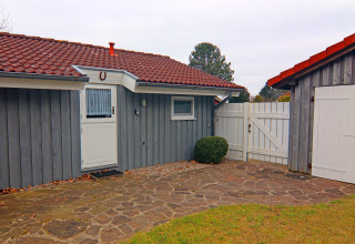 Outdoor view of Holiday home 'in Hünning' in Germany with grey wooden panels and red-tiled roof.