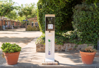 Ladestation für Elektrofahrzeuge bei Camping del Mar BUNGALOW PREMIUM in Spanien, umgeben von Pflanzen.