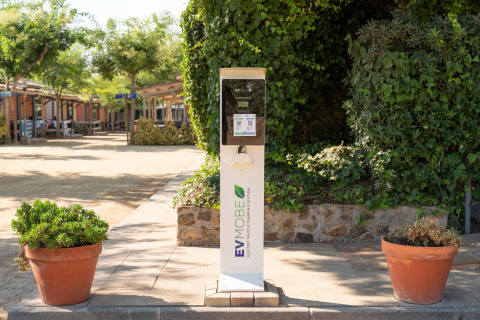 Ladestation für Elektrofahrzeuge bei Camping del Mar BUNGALOW PREMIUM in Spanien, umgeben von Pflanzen.
