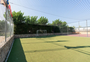 Pequeño campo de fútbol con césped artificial en Camping del Mar BUNGALOW PREMIUM en España, cercado y soleado.