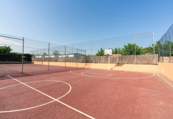 Basketballplatz im Freien bei Camping del Mar BUNGALOW PREMIUM in Spanien, umgeben von Zäunen und Bäumen.