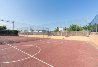 Basketballplatz im Freien bei Camping del Mar BUNGALOW PREMIUM in Spanien, umgeben von Zäunen und Bäumen.