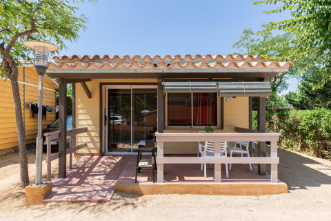 Außenansicht des Camping del Mar BUNGALOW PREMIUM Lodges in Spanien mit Terrasse und Gartenmöbeln.