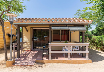 Vista exterior del lodge Camping del Mar BUNGALOW PREMIUM en España con terraza y muebles de jardín.