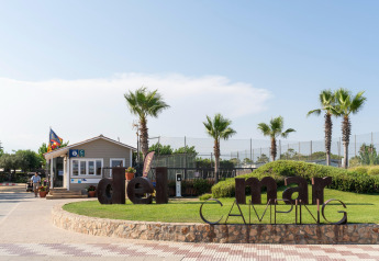 Entrada de Camping del Mar BUNGALOW PREMIUM en España, con palmeras, letrero y caseta de recepción.