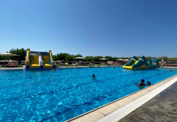 Outdoor swimming pool at Els Pins Mobile-Home Plus 2 in Spain, featuring inflatable water slides and guests.