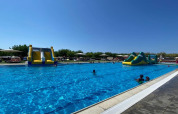 Piscina exterior en Els Pins Mobile-Home Plus 2, España, con toboganes inflables y huéspedes disfrutando.