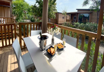 Outdoor terrace at Els Pins - Mobile-Home Plus 2 in Spain, with table, drinks, snacks and flowers.