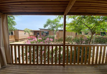 Vista desde la terraza del Els Pins Mobile-Home Plus 2 en España, con cabañas de madera y arbustos en flor.