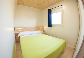 Lyst soveværelse i mobilhome Els Pins Mobile-Home Plus 2 i Spanien med dobbeltseng og vindue.