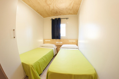 To enkeltværelser med grønne sengetæpper i Els Pins Mobile-Home Plus 2 i Spanien, lyst og enkelt design.
