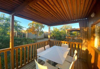 Solbeskinnet terrasse med træmøbler og udsigt over grønne omgivelser på Els Pins Mobile-Home Plus 2 i Spanien.