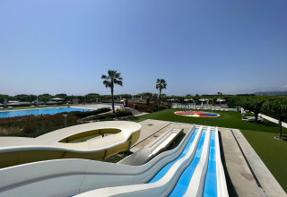 Photo of a glamping resort with swimming pools, water slides, palm trees and sun loungers under a blue sky.