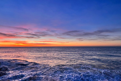 Smuk udsigt over havet ved solnedgang set fra et glampingophold, himlen i blå og orange nuancer.