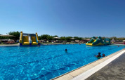 Outdoor swimming pool with inflatable water slides at Els Pins Mobile-Home Plus 3 in Spain, sunny day.
