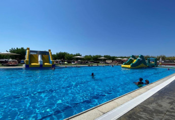 Piscina exterior con toboganes acuáticos inflables en Els Pins Mobile-Home Plus 3, España, día soleado.
