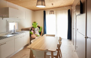 Cocina luminosa de casa móvil con mesa y niña abrazando mascota de tortuga en Els Pins, España.