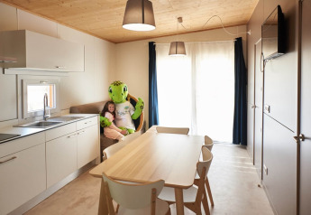 Cocina luminosa de casa móvil con mesa y niña abrazando mascota de tortuga en Els Pins, España.
