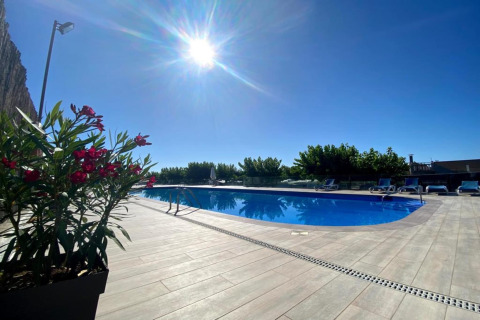 Solrig udsigt over swimmingpoolen ved Els Pins Mobile-Home Plus 3 i Spanien, omgivet af liggestole og planter.
