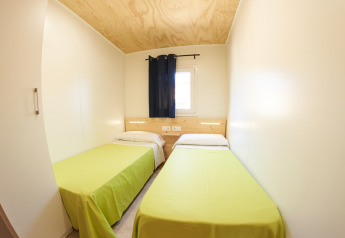 Dormitorio pequeño con dos camas individuales y colchas verdes en Els Pins Mobile-Home Plus 3, España.
