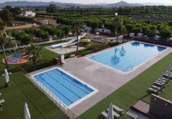 Piscinas exteriores y toboganes de agua en Els Pins Mobile-Home Plus 3 en España, rodeadas de naturaleza verde.
