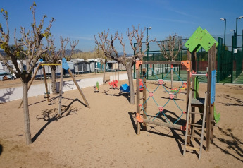 Parque infantil con columpios y juegos sobre arena junto a Els Pins Mobile-Home Plus 3 en España.