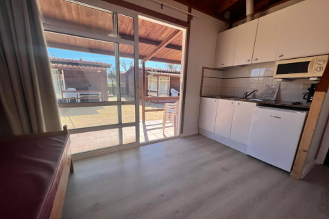 Interior view of kitchen and patio at Els Pins- Bungalow Comfort lodge in Spain, with garden visible outside.