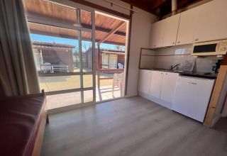 Interior view of kitchen and patio at Els Pins- Bungalow Comfort lodge in Spain, with garden visible outside.