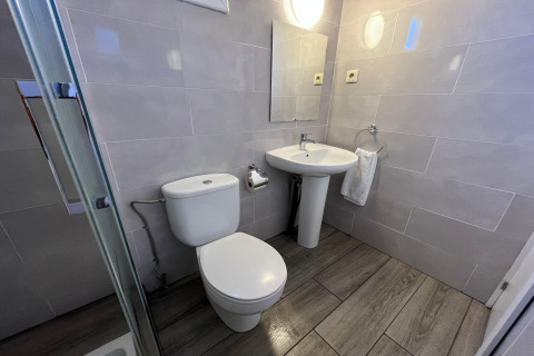 Modern bathroom at Els Pins- Bungalow Comfort in Spain featuring a toilet, sink, mirror, and towel.