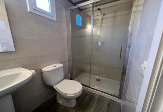 Modern bathroom at Els Pins- Bungalow Comfort in Spain with shower, toilet, and sink visible.