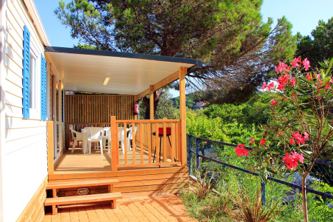 Casa mobile con veranda coperta, tavolo all’aperto, immersa nel verde al Camping Rocagrossa, Spagna.
