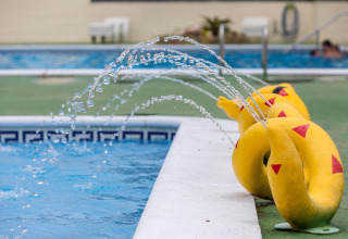 Vandstråler fra gule slangeformede springvand ved siden af poolen på Camping Rocagrossa i Spanien.