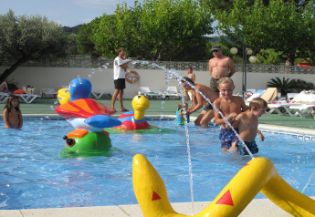 Des enfants jouent dans une piscine avec des jouets colorés au Camping Rocagrossa Mobile Home en Espagne.