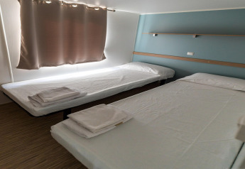 Due letti singoli con lenzuola bianche nel Camping Rocagrossa Mobile Home per 6 persone in Spagna.