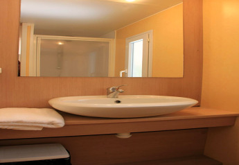 Bagno moderno in una casa mobile al Camping Rocagrossa in Spagna con lavabo, specchio e doccia.