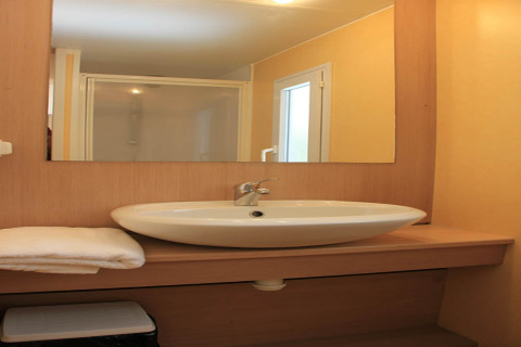 Bagno moderno in una casa mobile al Camping Rocagrossa in Spagna con lavabo, specchio e doccia.