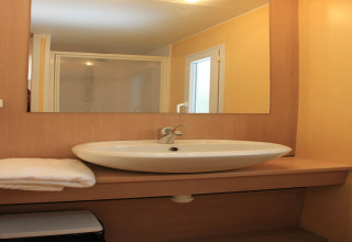 Moderne badkamer in een mobilhome op Camping Rocagrossa, Spanje, met lavabo, spiegel en douche.