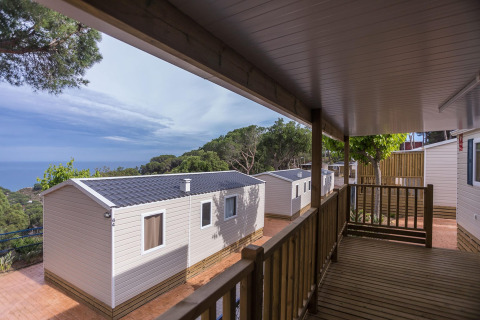 Udsigt fra verandaen på Camping Rocagrossa Mobile Home til seks personer, omgivet af træer i Spanien.