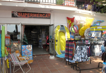 Ingresso al supermercato del Camping Rocagrossa in Spagna, con articoli da spiaggia e gonfiabili esposti fuori.