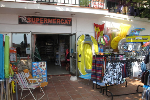 Ingresso al supermercato del Camping Rocagrossa in Spagna, con articoli da spiaggia e gonfiabili esposti fuori.