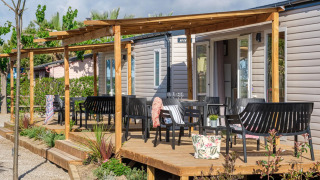 Mobil-home avec terrasse en bois et chaises noires au CAMPING ESTIVAL VENDRELL PLATJA Méditerranéen 4 pers.