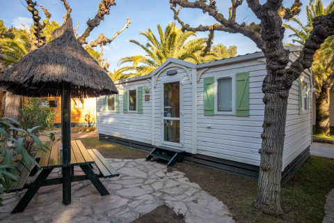 Vista exterior de Torre del Sol COTTAGE ACACIA con mesa de picnic techada y contraventanas verdes.